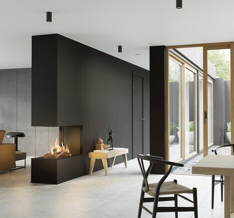 VISIO 90 RD gas fireplace fits perfectly as a room divider in a black wall between the living room and dining room and gives structure to the simply decorated living space
