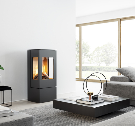 Gas stove NEXO 100 in black with steel door and two side windows in a modern, bright living room