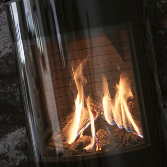 Firebox of the VIVA L gas stove with glass door and high-quality artificial logs made of ceramic