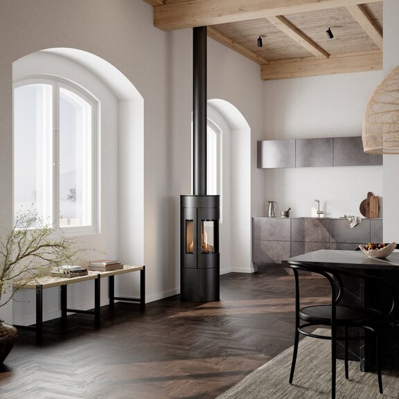 Gas stove VIVA 120 L in black with steel door and side window in a kitchen with dining table in Nordic style