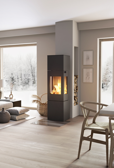 Wood stove NEXO 160 in black with steel door and side window in the centre of the living room between the dining area and living room