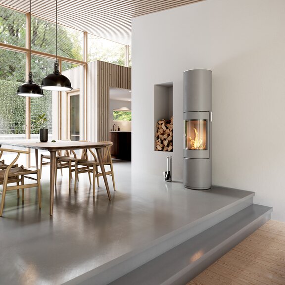 Wood stove PILAR in nickel with steel door and stainless steel handle in the dining room with modern furnishing style