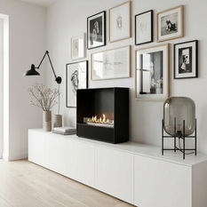 Bioethanol fireplace Milan with a black front panel, freestanding on a white sideboard in front of a picture wall
