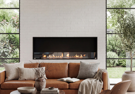 Montreal Front Bioethanol fireplace in the living room, featuring a brown leather sofa set against a light-coloured stone wall