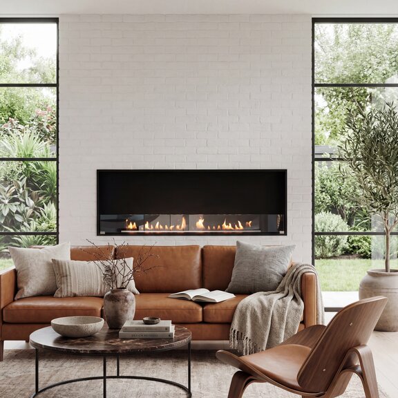 Montreal Front Bioethanol fireplace in the living room, featuring a brown leather sofa set against a light-coloured stone wall